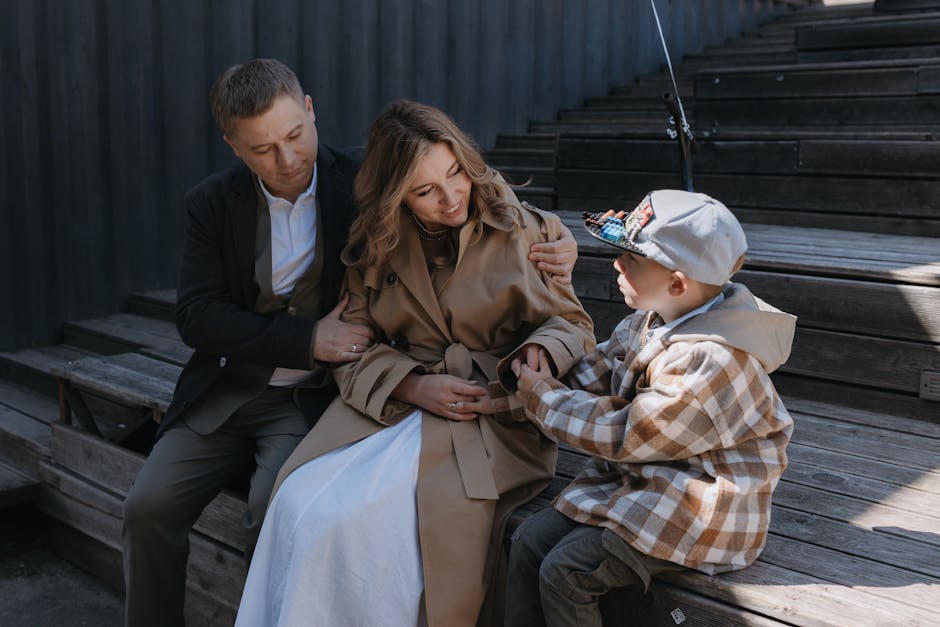 A happy family of three sitting on steps outdoors, sharing moments of affection and joy.